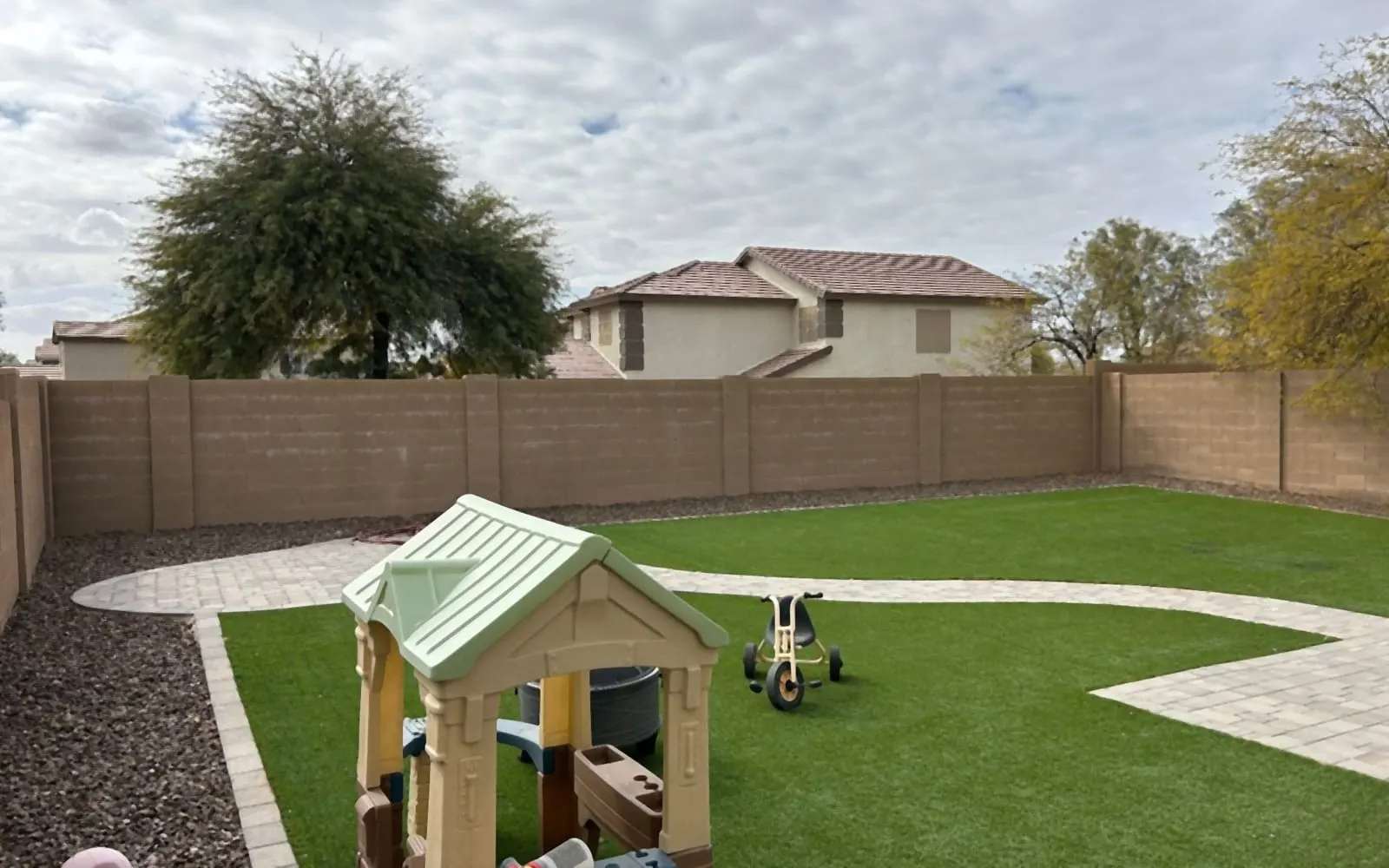 The same backyard after: weeds removed, clean turf, rock and paver path