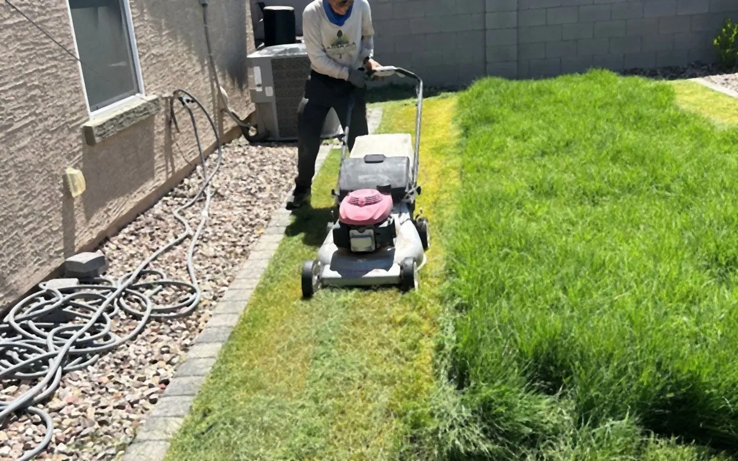 Crew member mowing an overgrown lawn