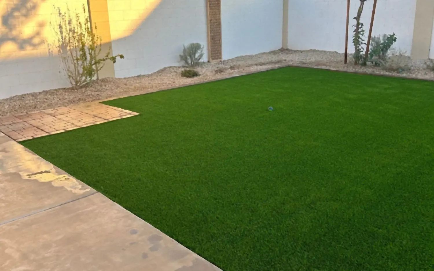 The same backyard after: new artificial turf with a paver border